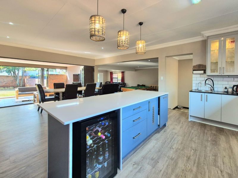 Spacious open-plan kitchen and living area featuring a modern island with wine cooler, quartz countertops, and seamless flow to the outdoor patio.