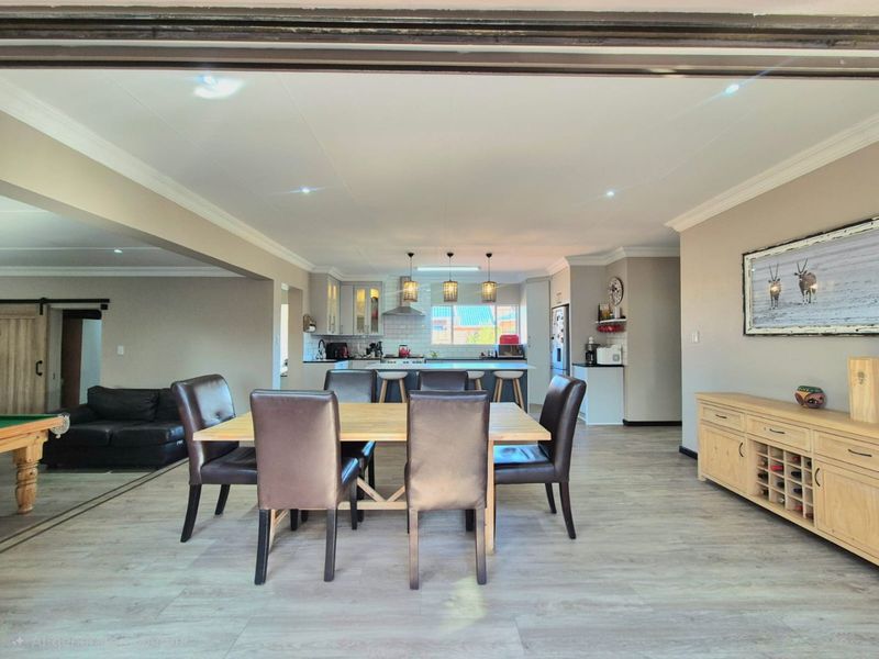 Spacious open-plan living and dining area featuring a modern kitchen with a central island, recessed lighting, and durable laminate flooring throughout.