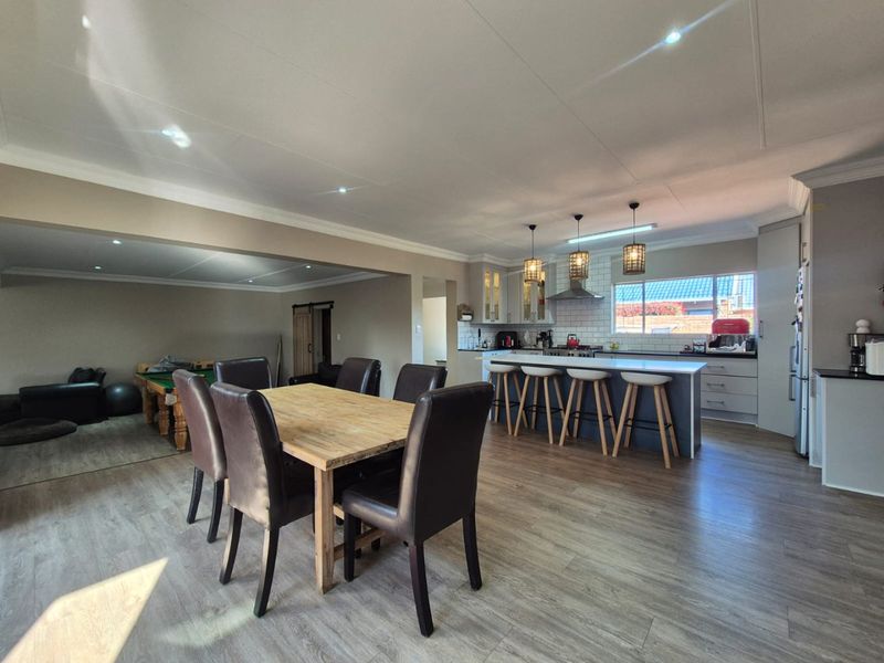 Spacious open-plan living and dining area featuring a modern kitchen with a central island, subway tile backsplash, and contemporary lighting fixtures.
