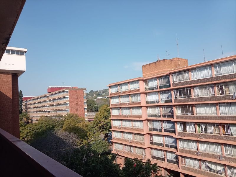 An elevated view overlooking surrounding apartment buildings and mature trees in a residential urban setting.