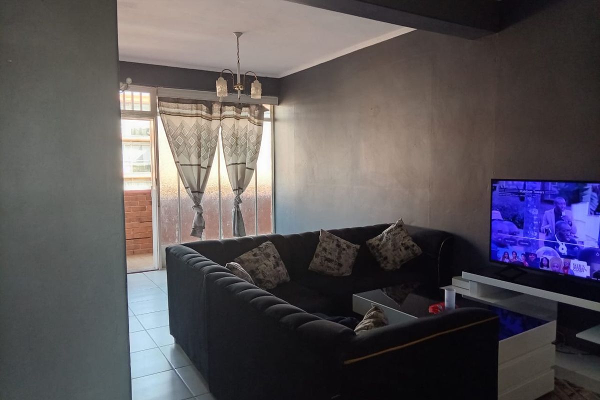 A living room featuring tiled flooring, a ceiling light fixture, and a sliding glass door leading to an outdoor area.