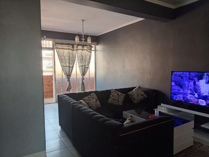 A living room featuring tiled flooring, a ceiling light fixture, and a sliding glass door leading to an outdoor area.