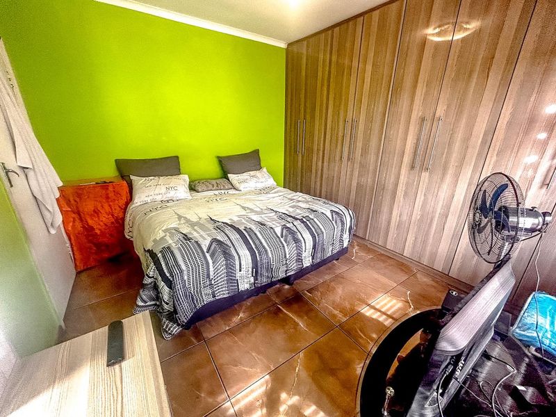 A bedroom featuring tiled flooring and extensive built-in wooden cupboards, providing ample storage space.