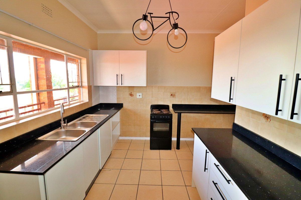 Functional kitchen featuring white cabinetry, black granite countertops, double basin sink, and tiled flooring with a classic layout.