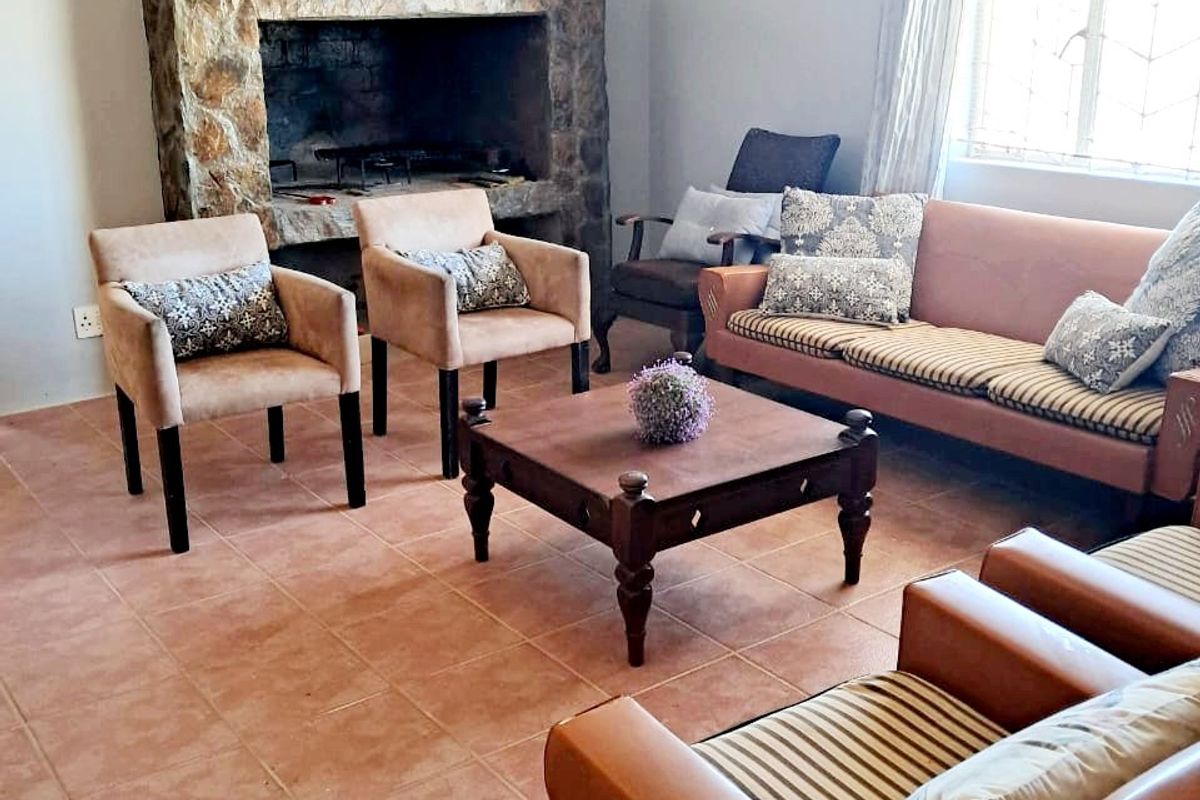 A cozy living room featuring a prominent stone fireplace, tiled flooring, and classic ceiling cornice detail, providing a warm and inviting atmosphere.