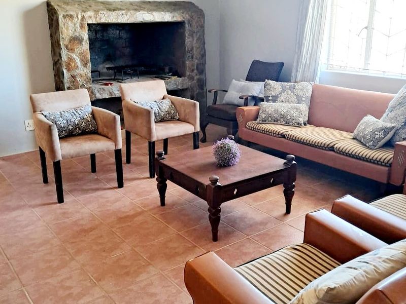 A cozy living room featuring a prominent stone fireplace, tiled flooring, and classic ceiling cornice detail, providing a warm and inviting atmosphere.
