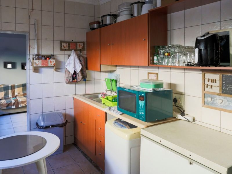A functional kitchen area featuring built-in cabinetry, tiled backsplash, and a stainless steel sink, offering potential for modernization and aesthetic updates.