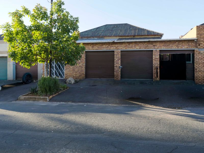 Front exterior view of a residential property featuring a triple garage with metal roller doors and an asphalt driveway.