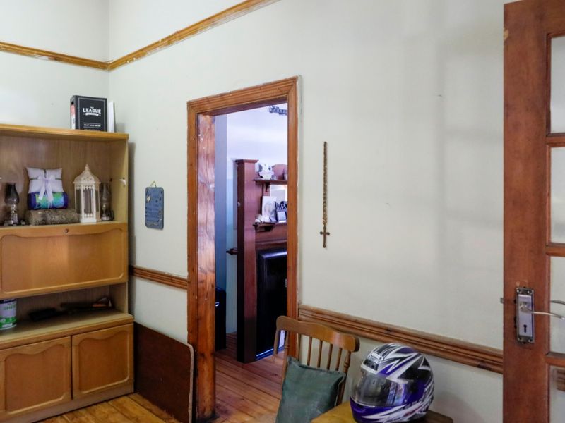 A hallway featuring traditional timber door frames, dado rails, and picture rails with original timber flooring.