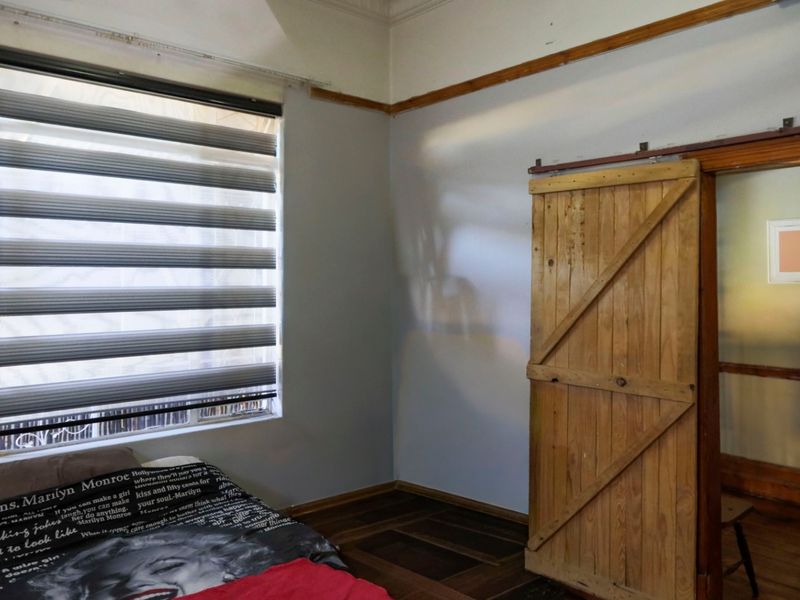 Bedroom featuring wooden parquet flooring, a rustic sliding barn door, and modern zebra blinds, offering a blend of classic and contemporary elements.