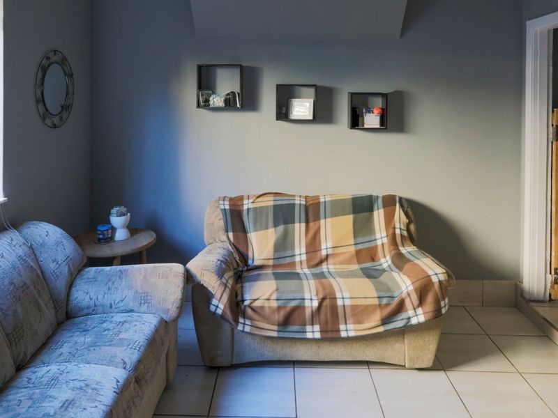 A living room area featuring tiled flooring and a distinctive wooden door with decorative metal hinges.
