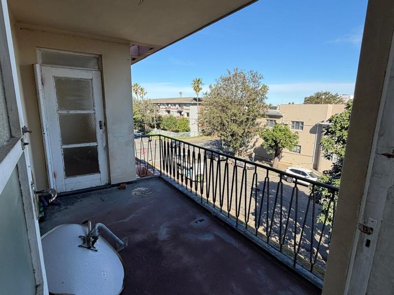 An outdoor balcony featuring a metal balustrade and concrete flooring, requiring maintenance and cosmetic updates to improve its overall appearance.