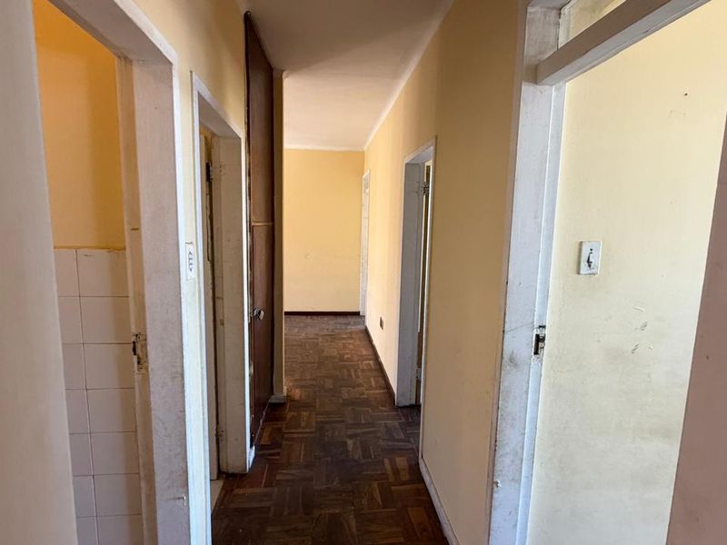 A functional hallway featuring traditional parquet flooring and multiple doorways leading to various rooms, requiring cosmetic updates to refresh the space.