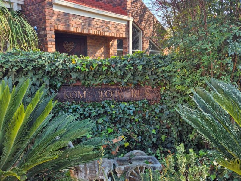 A view of the front facade featuring classic face brick construction, a prominent chimney stack, and a landscaped garden entrance.