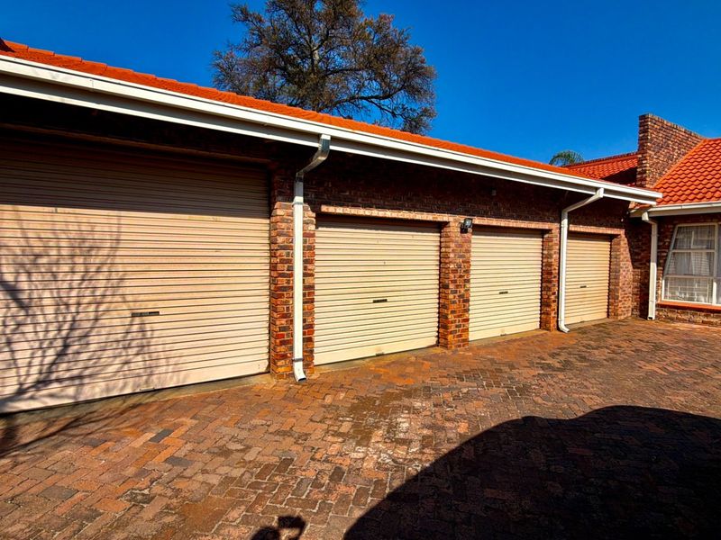 A triple garage with roller doors and a brick facade, featuring a paved driveway and tiled roof.