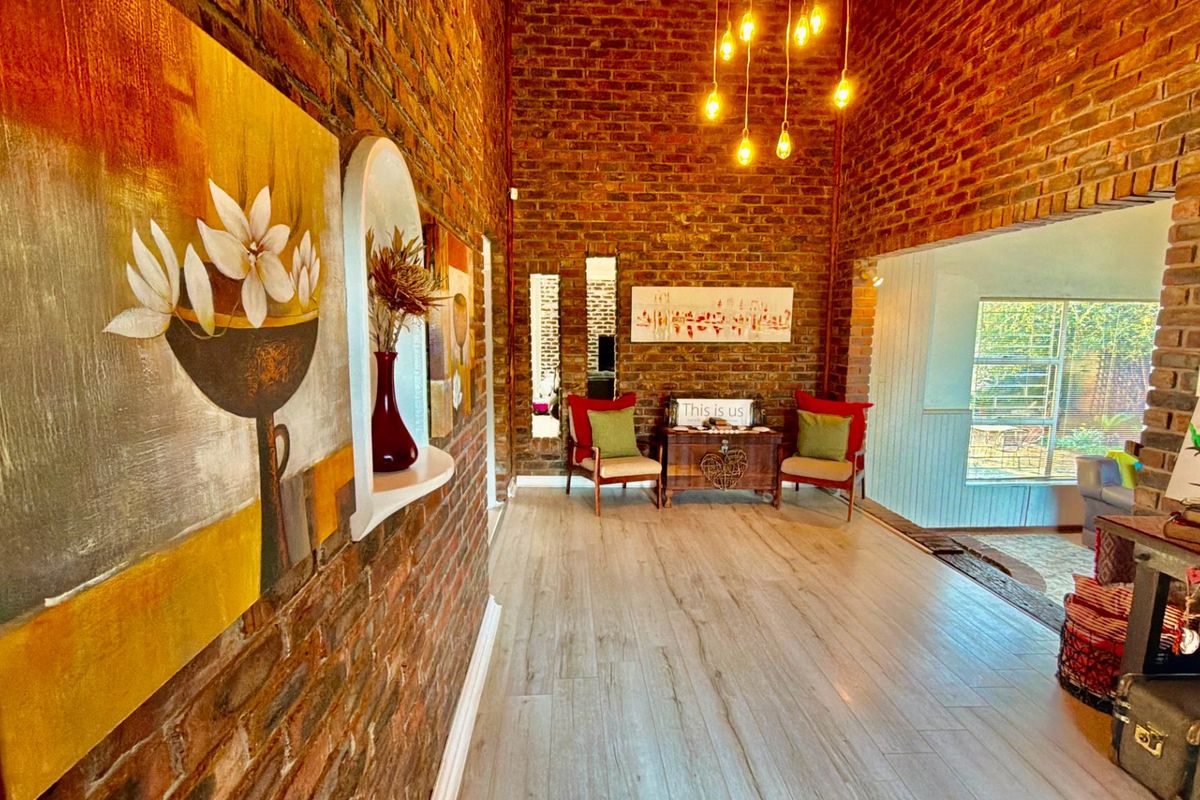 A characterful living area featuring exposed brick walls, modern laminate flooring, and warm pendant lighting, creating a cozy and inviting atmosphere.