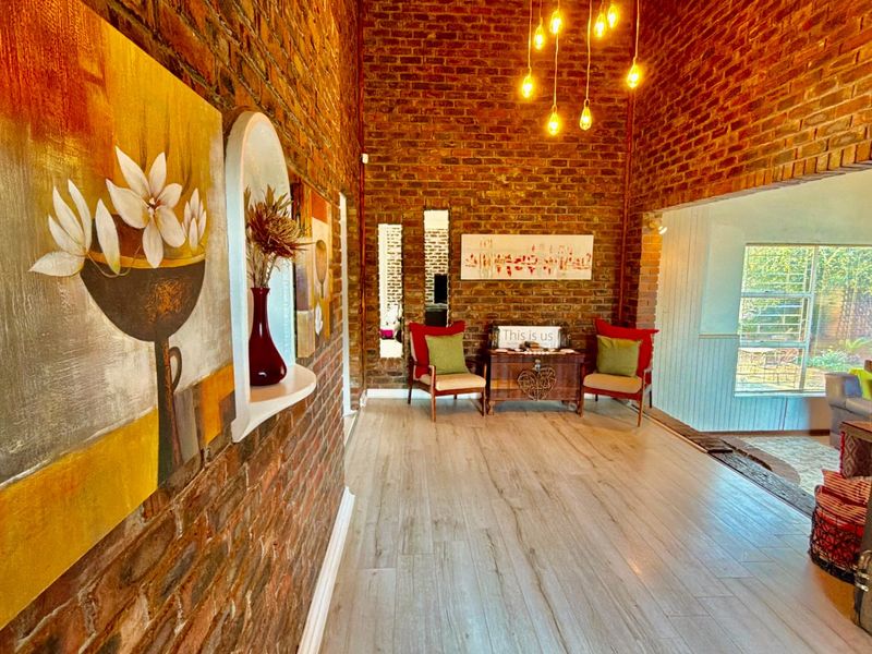 A characterful living area featuring exposed brick walls, modern laminate flooring, and warm pendant lighting, creating a cozy and inviting atmosphere.