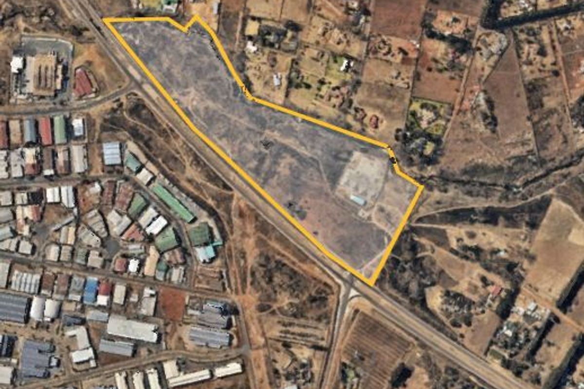 Aerial view of a large, vacant residential plot with clear boundary markings, situated in a developed suburban area.