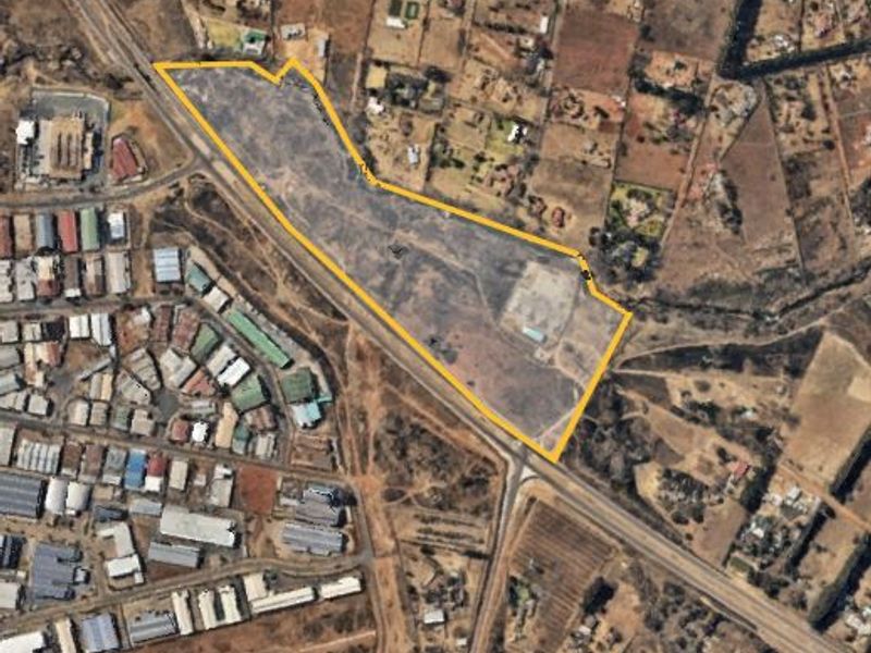 Aerial view of a large, vacant residential plot with clear boundary markings, situated in a developed suburban area.