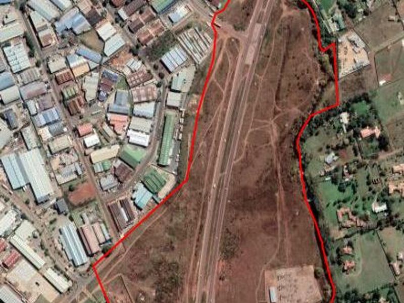 An aerial view of a large, undeveloped residential land parcel situated adjacent to industrial and residential zones.