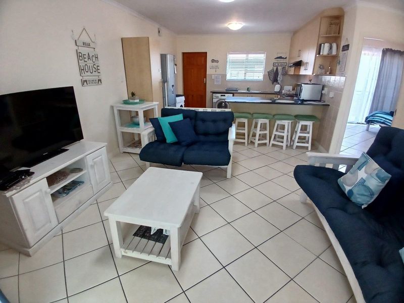 Open plan living area featuring tiled floors and a functional kitchen with a breakfast bar, creating a cohesive and practical living space.