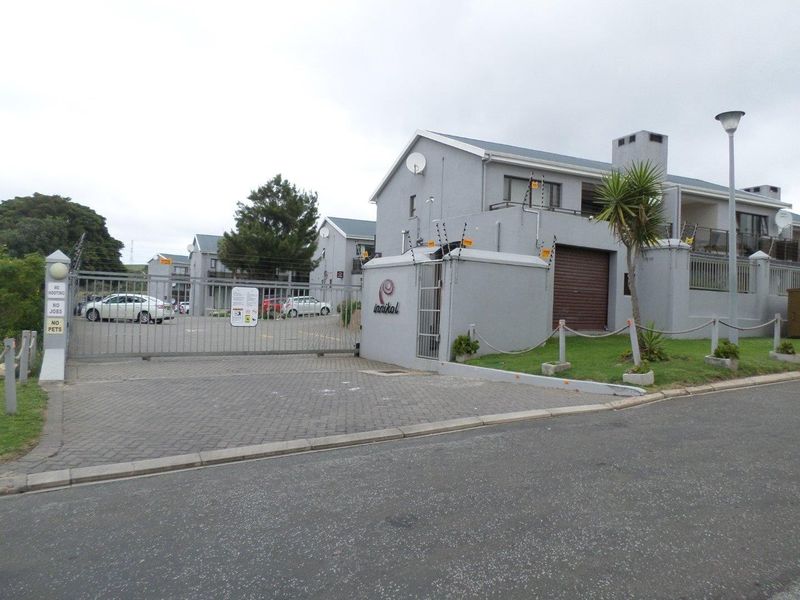 Front view of the apartment complex entrance featuring a secure gated access point, paved driveway, and established exterior building finishes.