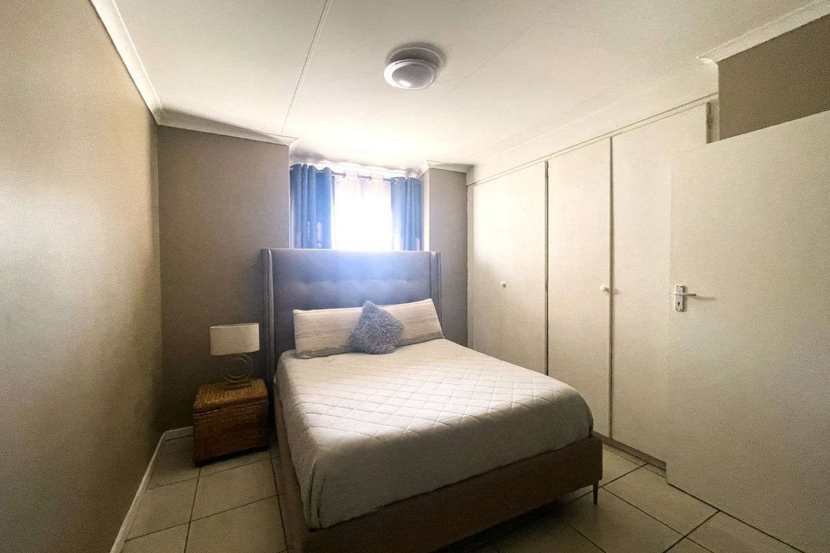 A functional bedroom featuring tiled flooring, built-in cupboards for storage, and neutral wall tones, offering a comfortable and practical living space.