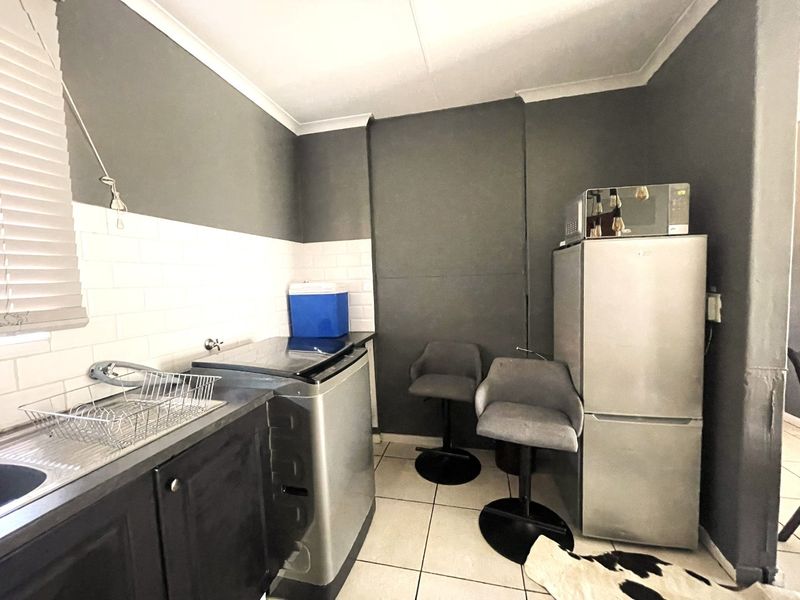 A compact kitchen area featuring a subway tile backsplash, stainless steel sink, and tiled flooring with dark grey painted walls.