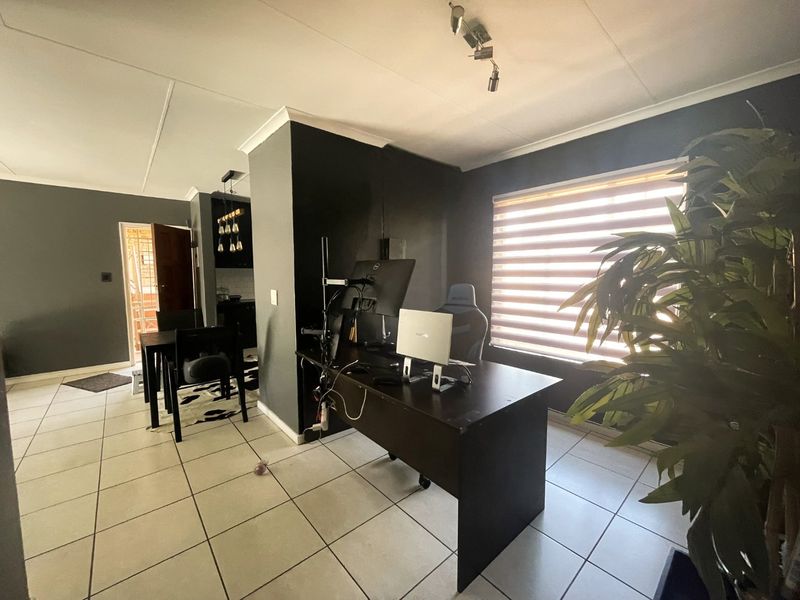 Open plan living area featuring tiled flooring, modern spotlighting, and zebra blinds, providing a versatile space for a home office and dining area.