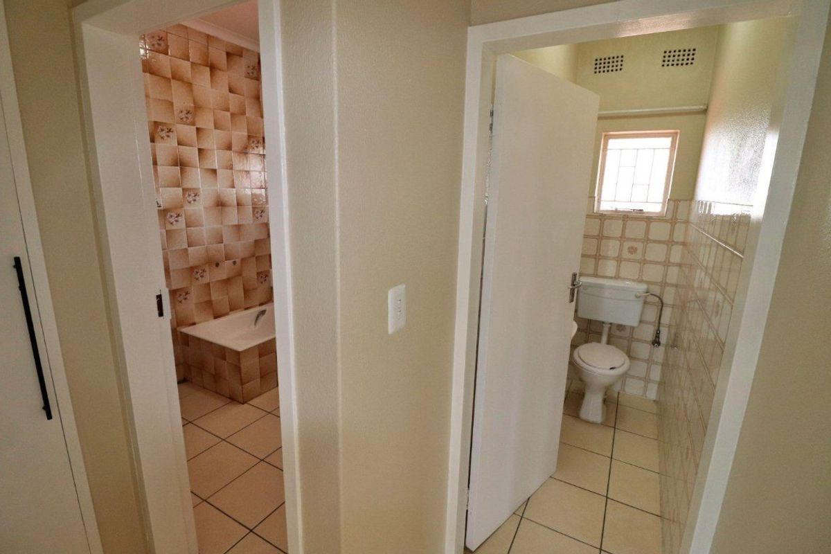 A functional bathroom layout featuring a separate bathtub area and a private toilet room with dated ceramic tile finishes.