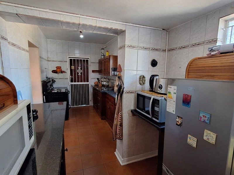 A functional kitchen featuring tiled walls, granite countertops, and built-in wooden cabinetry, providing a practical workspace with secure access points.