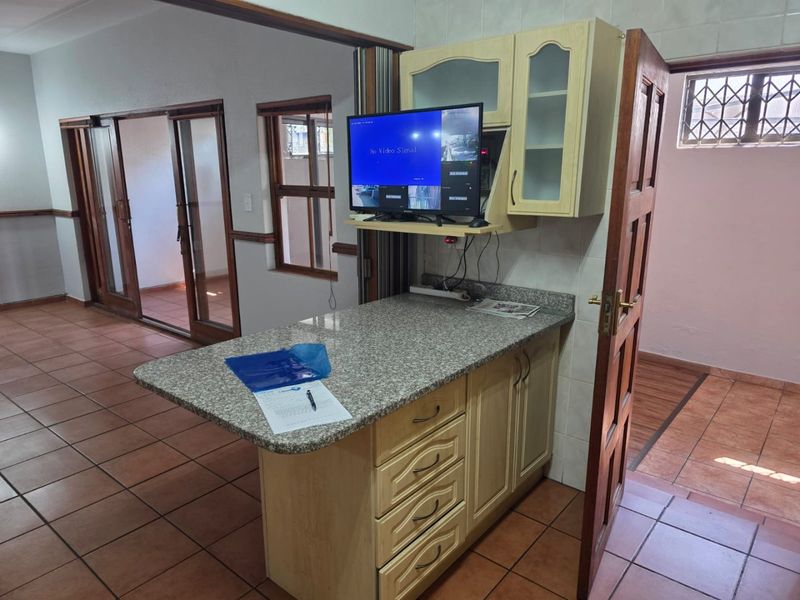 A functional kitchen area featuring granite countertops, built-in cabinetry, and tiled flooring, with direct access to adjacent living spaces via sliding glass doors.