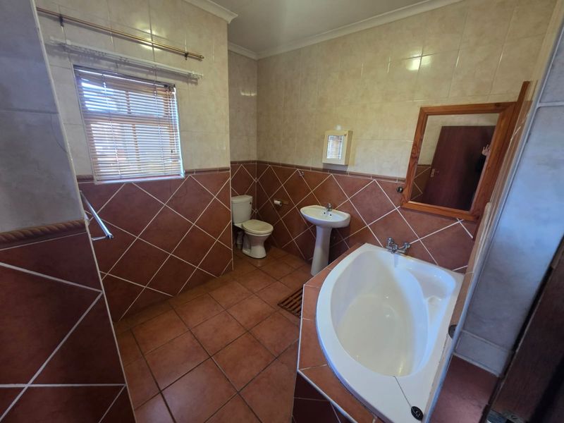 A dated bathroom featuring a pedestal basin, toilet, and built-in bathtub with tiled finishes throughout.