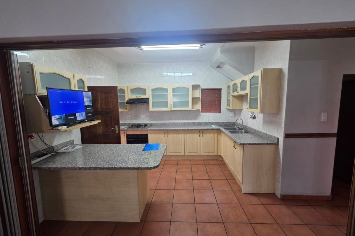 A functional kitchen featuring light wood cabinetry, granite countertops, a breakfast nook, and tiled flooring, equipped with a gas hob and built-in oven.