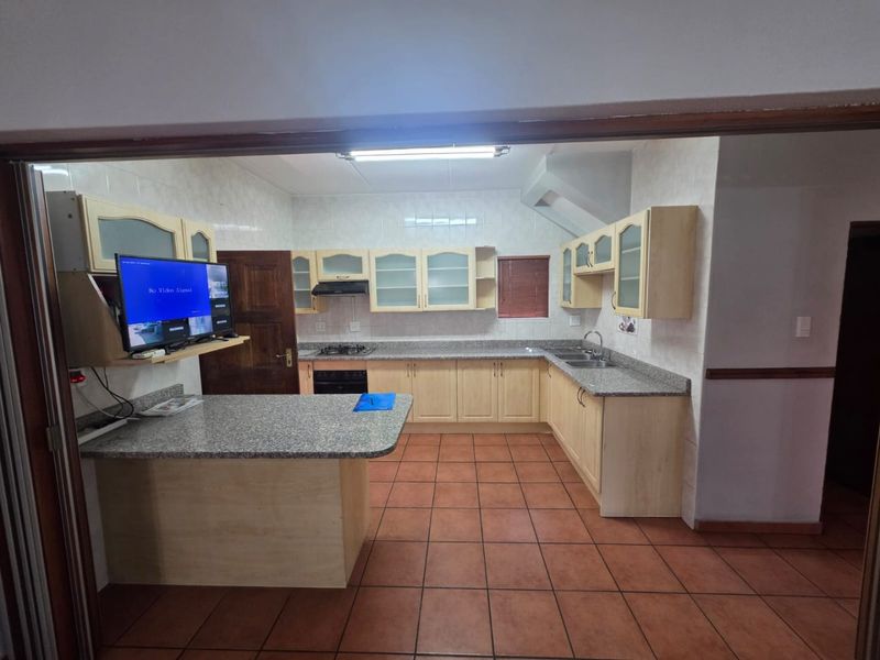 A functional kitchen featuring light wood cabinetry, granite countertops, a breakfast nook, and tiled flooring, equipped with a gas hob and built-in oven.