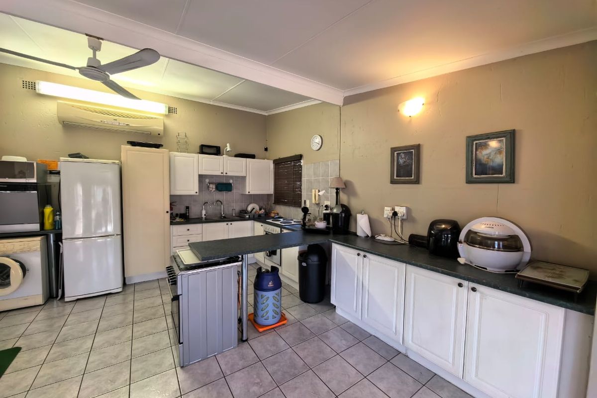 Functional kitchen featuring white cabinetry, laminate countertops, tiled flooring, and integrated climate control, offering a practical layout for daily meal preparation.