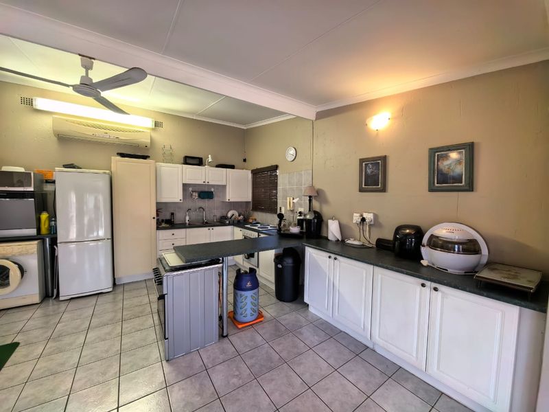 Functional kitchen featuring white cabinetry, laminate countertops, tiled flooring, and integrated climate control, offering a practical layout for daily meal preparation.