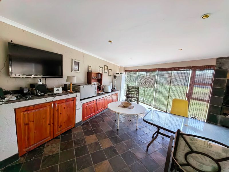 Covered patio area featuring built-in wooden cabinetry, stone tile flooring, and large sliding glass doors providing access to the garden.
