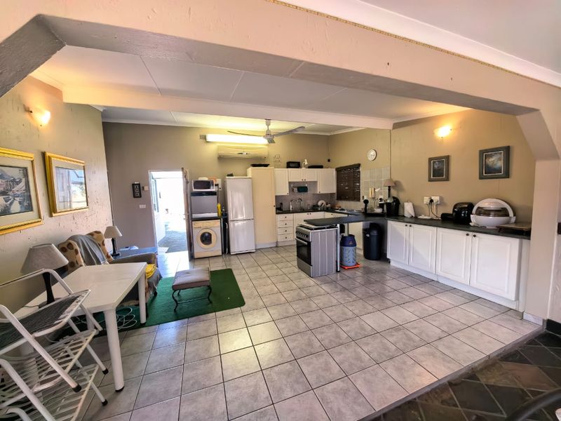 Spacious open-plan kitchen and living area featuring tiled flooring, built-in cabinetry, and a wall-mounted air conditioning unit.