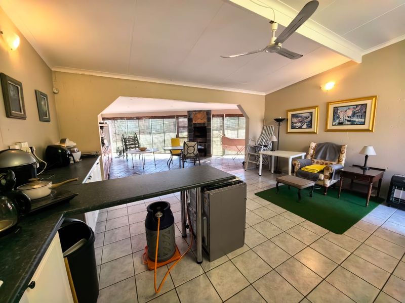 Open-plan living area featuring a kitchen with laminate countertops, tiled flooring, a ceiling fan, and a built-in fireplace in the adjacent lounge space.