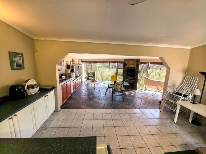Open-plan living and kitchen area featuring built-in cabinetry, a fireplace, and tiled flooring, offering a functional space with potential for modern updates.