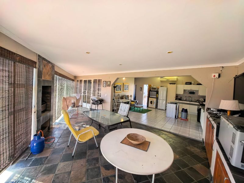 Spacious open-plan living area featuring a built-in fireplace, tiled flooring, and an integrated kitchen with functional cabinetry and sink.