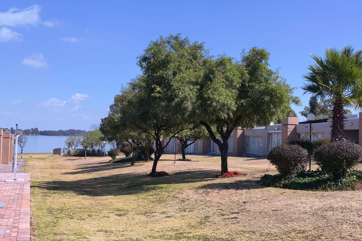 A view of the rear exterior featuring a landscaped garden, paved walkway, and direct access to the property via sliding glass doors.
