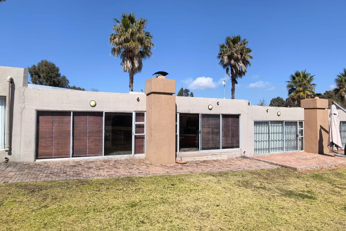 Rear view of the property featuring a brick paved patio, sliding glass doors with security gates, and an external chimney stack.