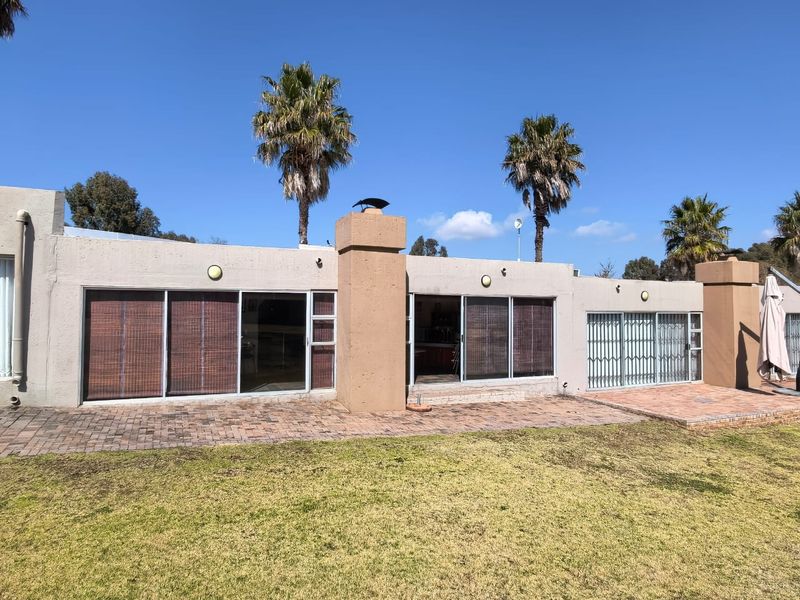 Rear view of the property featuring a brick paved patio, sliding glass doors with security gates, and an external chimney stack.