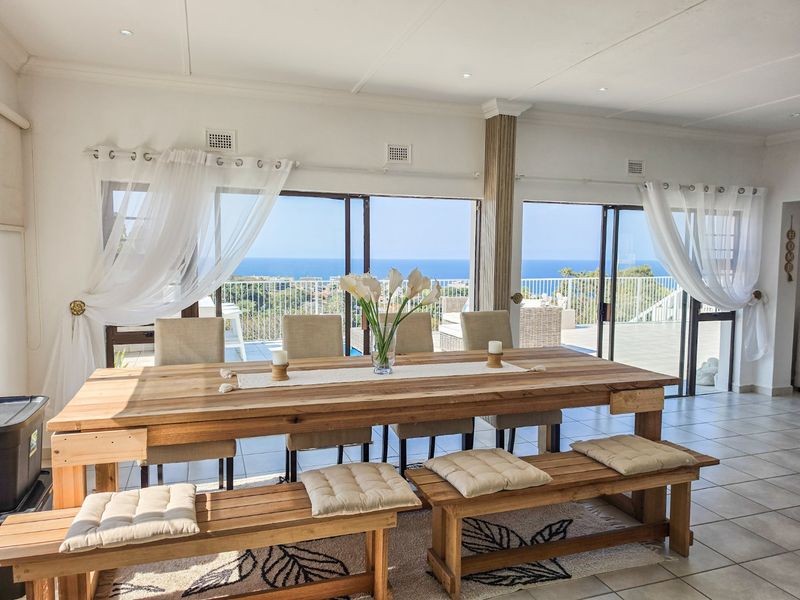 Spacious dining area featuring tiled flooring, recessed lighting, and large sliding glass doors that open to a scenic ocean view.