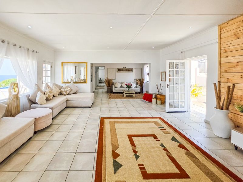 Spacious open-plan living area featuring neutral tiled flooring, recessed lighting, and direct access to the outdoors through classic french doors.