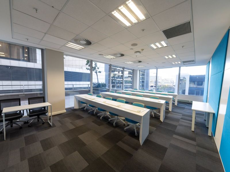 Modern commercial office space featuring large floor-to-ceiling windows, suspended ceilings with integrated lighting, and acoustic wall paneling.