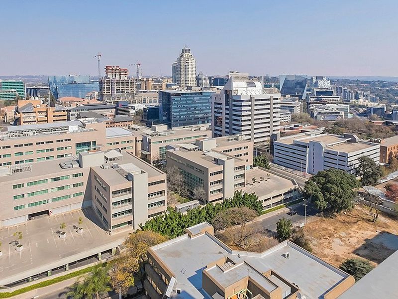 An aerial view of a commercial business district featuring multiple office buildings, parking facilities, and surrounding urban infrastructure.