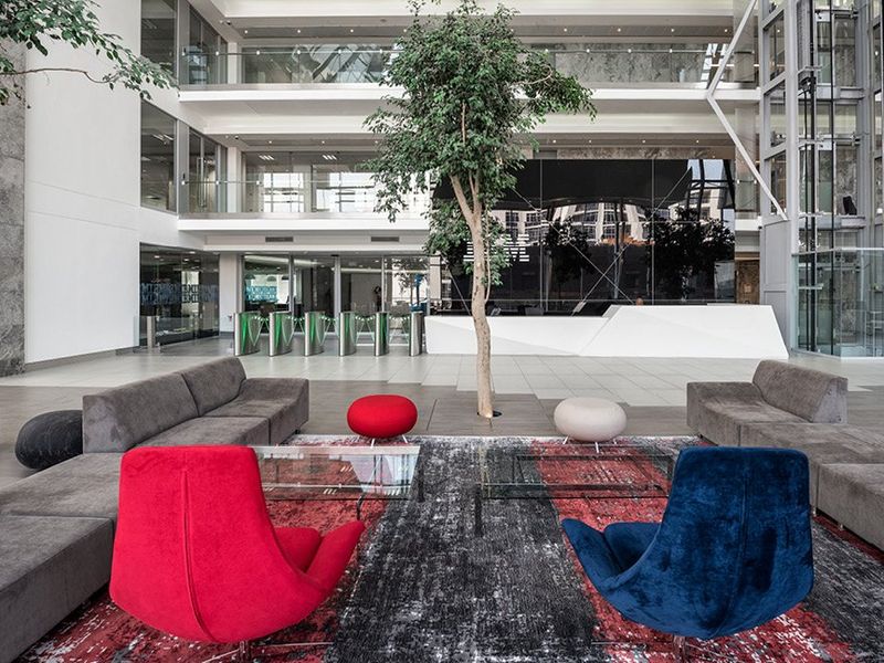 Spacious modern commercial atrium featuring a multi-level design, glass elevator, security turnstiles, and a contemporary reception area with high-end finishes.